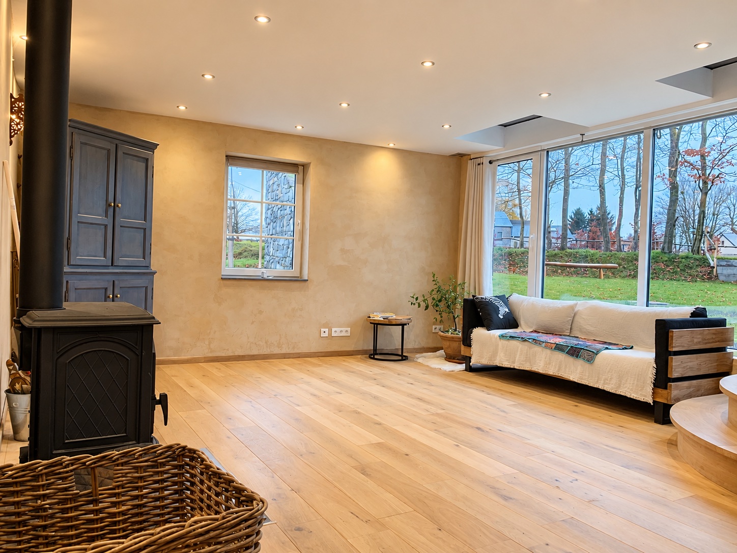 Salon lumineux du gîte avec poêle à bois et grande baie vitrée
